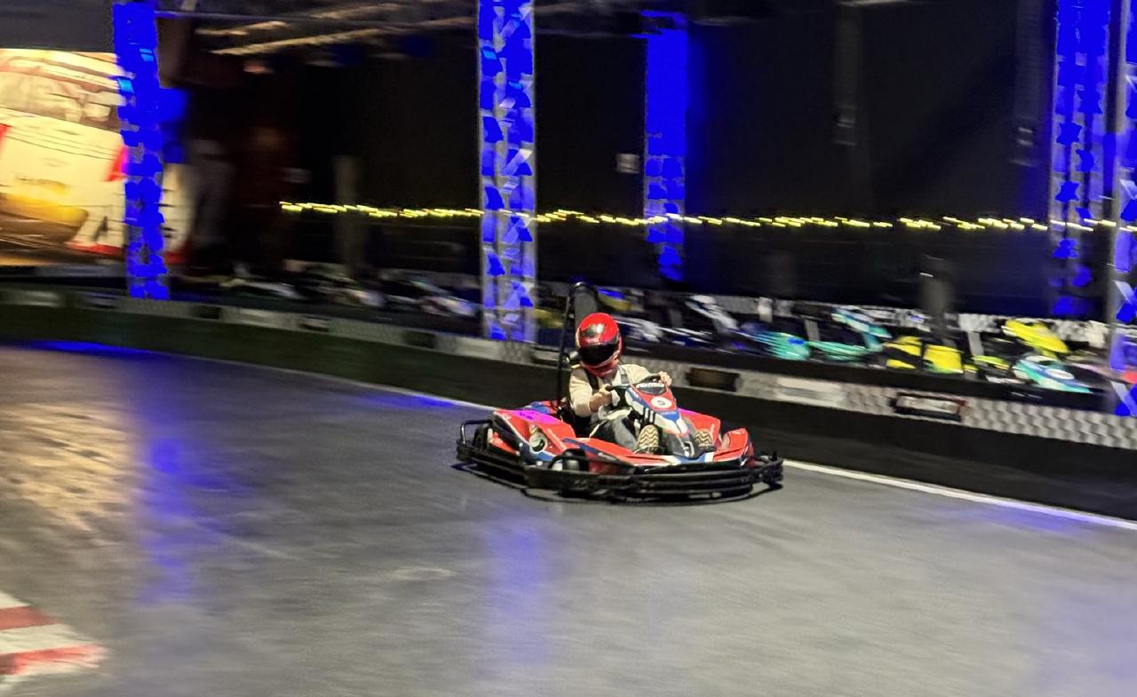 Eine Person mit Helm fährt mit einem Kart rasant um die Kurve